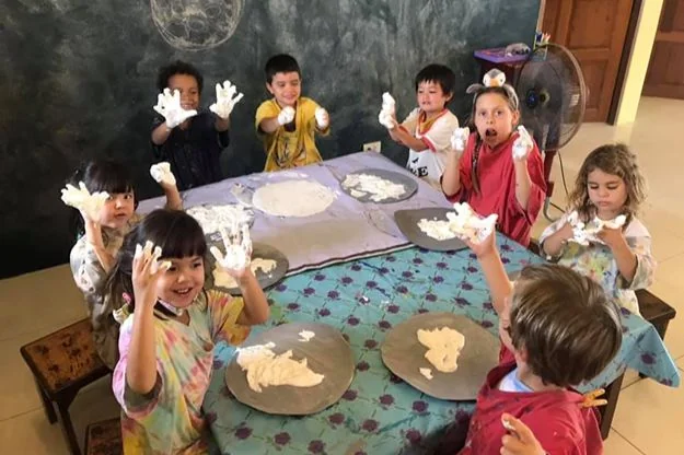 Teacher guiding children through a creative learning activity at Shining Stars School Kamala