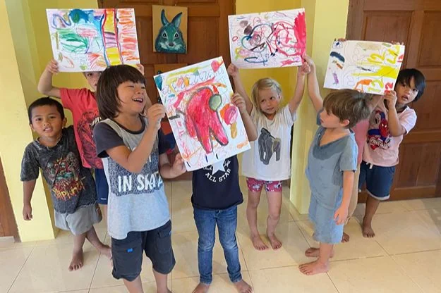 Children presenting artwork with their teacher at Shining Stars preschool in Phuket